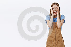 Mind going crazy from awesome surprise. Portrait of impressed and amazed cute charming young woman in cute overalls