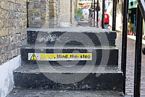 Mind The Step Sign on Worn and black Steps