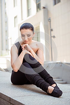 Minded ballerina sitting on the balusters