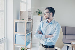 Minded entrepreneur standing with crossed arms and looking in th