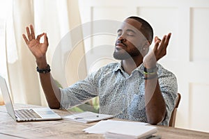 Mindful african american guy relaxing during remote working.