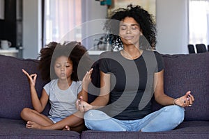 Mindful african mom with funny kid daughter doing yoga together