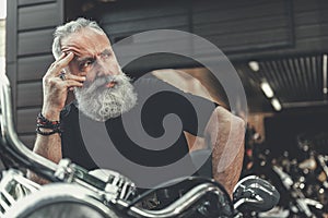 Mindful elder man locating on motorbike photo