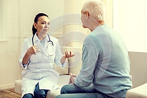 Mindful female medical worker talking to senior patient