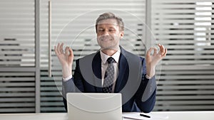 Mindful happy businessman relaxing meditating sit at office desk
