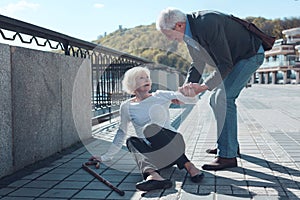 Mindful man helping elderly female stranger to stand up