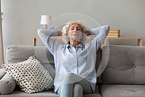 Mindful older mature grandmother sleeping on cozy sofa.