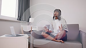 Mindfulness concept. Young spiritual woman sitting on the couch and meditating