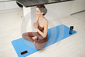 Mindfulness and meditation. Young spiritual woman, does yoga, sits in meditation pose in headphones, with workout