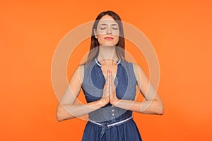 Mindfulness, zen practice. Happy calm brunette woman in denim dress doing yoga exercise with hands together