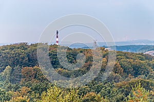 Mine shaft tower and factory chimney emerging form trees peaks, lightened by rising sun. Aerial view on autumn forest. Forest,