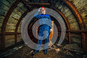 A miner in a coal mine stands near a trolley. Copy space. Passages and corridors in a coal mine.