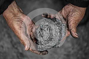 Miner dirty hands holding piece of fossil lignite coal mine