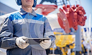 Miner in helmet with tablet computer on background of tunneling machine. Concept banner smart industrial mining in mine