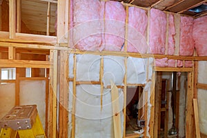 Mineral glass wool in a wooden frame on a inclined wall near the wooden ceiling in a private house