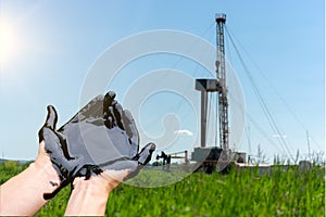 Mineral oil in the hands of man. Caucasian hands cupped with black rock-oil. Oil and Gas Drilling Rig.