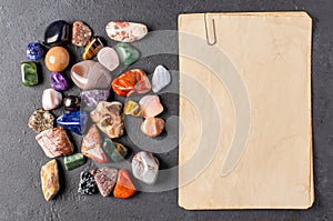 Mineral stones and an old piece of paper. Black concrete background. The concept of using minerals in astrology and