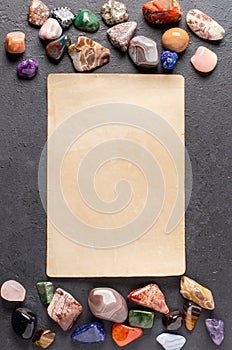 Mineral stones and an old piece of paper. Black concrete background. The concept of using minerals in astrology and