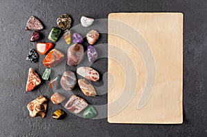 Mineral stones and an old piece of paper. Black concrete background. The concept of using minerals in astrology and