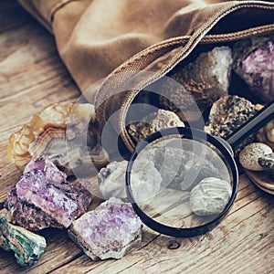 Mineral stones set and magnifying glass, backpack of geologist.