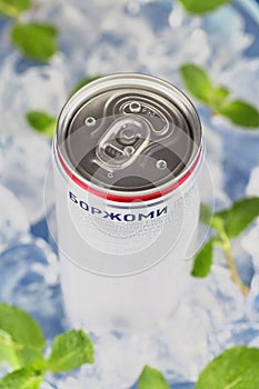 Mineral water Borjomi in an aluminum tin on the background of ice cubes and fresh mint leaves. Tasting in Minsk 20.02