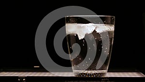 Mineral water in glass with ice on a black background.