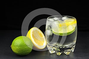 Mineral water in the glass with ice cubes, lime and lemon