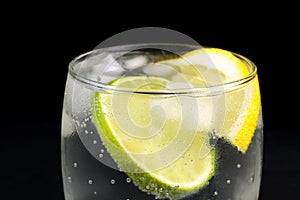 Mineral water in the glass with ice cubes, lime and lemon