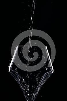 Mineral water is poured into a glass. Black background.