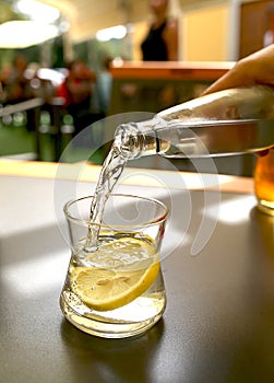 Mineral water is poured into a glass on a table