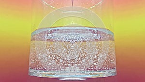 Mineral water poured into a water glass with splashes and air bubbles