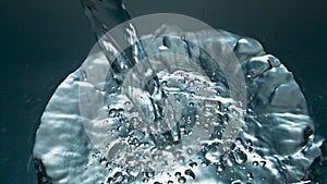 Mineral water pouring transparent glass closeup. Blebs going up smooth liquid