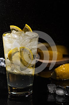 Mineral water with sliced lemon, ice cubes and water splash on black background horizontal view