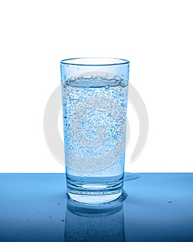 mineral water in transparent glass with drops and bubbles isolated over white, blue background, close up