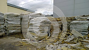 Mineral wool waste in plastic wrap outside. Territory of old abandoned factory. Pile of rubbish. Mess. Substandard. Construction a