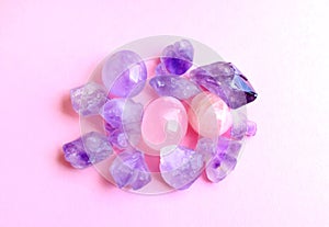 Minerals of gemstones on a pink background. Beautiful purple amethyst crystals and rose quartz minerals