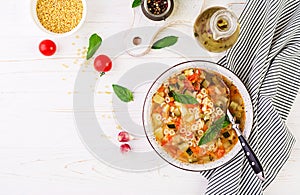 Minestrone, italian vegetable soup with pasta on white table.