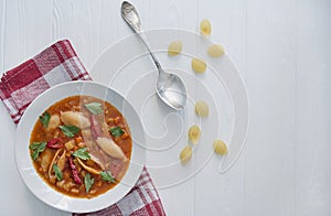 Minestrone soup with pasta and herbs. Italian Cuisine. White wood background. Place for text