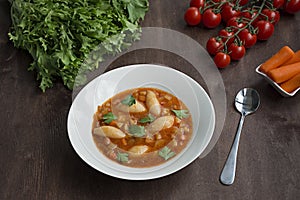 Minestrone soup with pasta and herbs. Italian food.Dark wooden background. Place for text