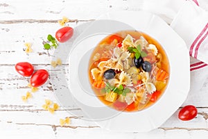 Minestrone, vegetarian soup with pasta and vegetables on white wooden rustic background. Traditional italian food