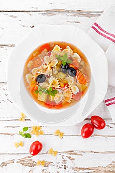 Minestrone, vegetarian soup with pasta and vegetables on white wooden rustic background. Traditional italian food