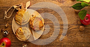 Mini Apple pie tartlets with walnut on wooden table. Delicious dessert for autumn winter dinner.Top view