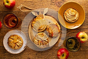 Mini Apple pie tartlets with walnut on wooden table. Delicious dessert for autumn winter dinner.Top view