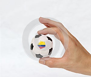 Mini ball of football in hand, hold it with two finger on white background.