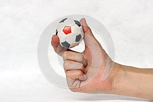 Mini ball of football in hand and one black point of football is China flag, hold it with two finger on white background