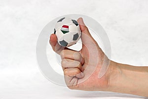 Mini ball of football in hand and one black point of football is Hungary flag, hold it with two finger on white background