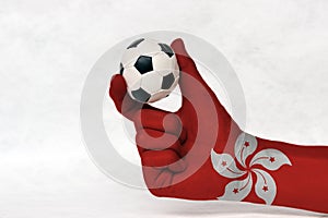 Mini ball of football in Hong kong flag painted hand, hold it with two finger on white background.