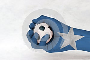 Mini ball of football in Somalia flag painted hand on white background.