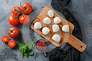 Mini balls of mozzarella cheese, on chop wood board ingredients for salad Caprese. over grey background. Top view