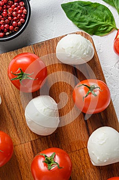 Mini balls of mozzarella cheese, on chop wood board ingredients for salad Caprese. over white background. close up selective focus